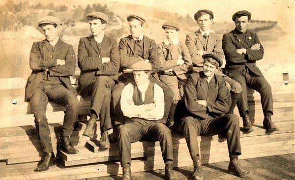 Eight unidentified men sitting on woodJan Shuttleworth collection, 1910