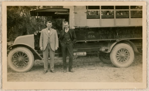 Two men standing by a bus, 1900